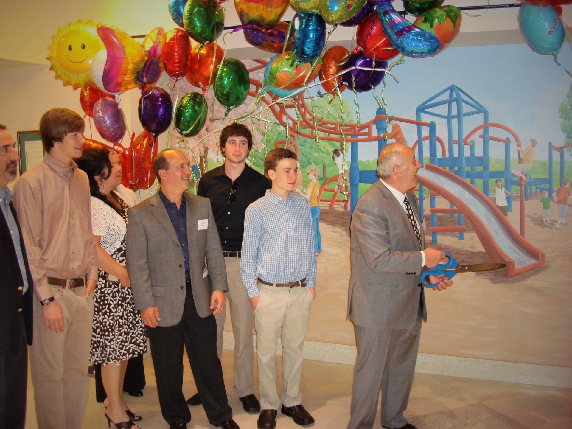 A Man in a Grey Suit Unveiling a Mural With a Group